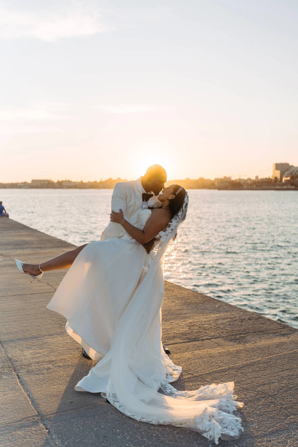 Groom dipping the bride for a kiss at golden hour overlooking the sea after their Forte da Cruz wedding ceremony.