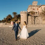 Wedding couple walking together in front of Forte da Cruz in Estoril, combining historic architecture with a natural and timeless seaside setting.