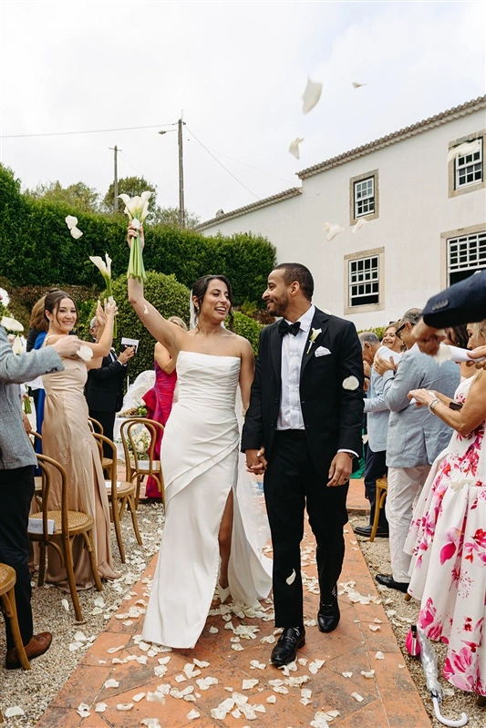 Bride and groom walking down the aisle after their Jewish wedding ceremony in Portugal as guests throw petals in celebration.