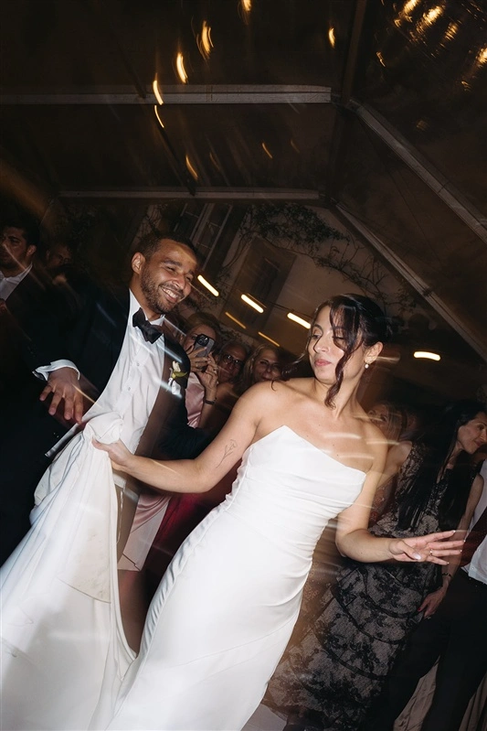 Bride and groom dancing energetically during their Jewish wedding reception in Portugal surrounded by guests and party lights in quinta d Carlos