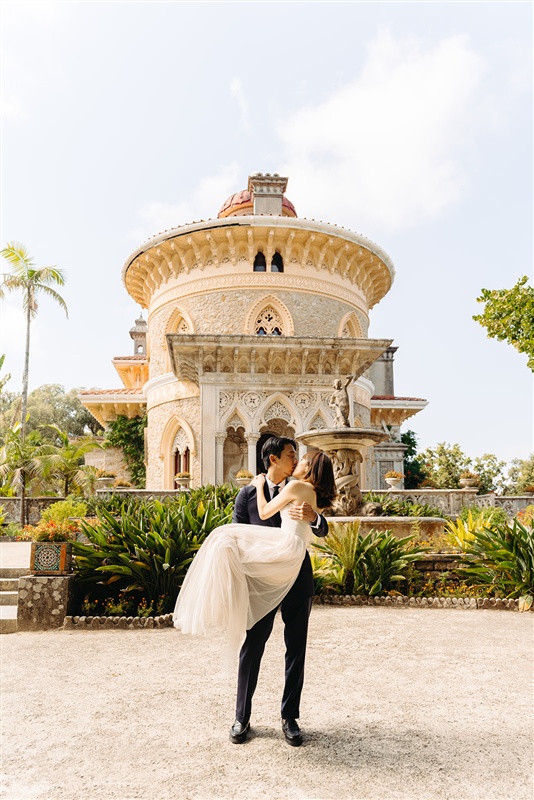 Romantic wedding portrait under a rustic stone arch at Monserrate Palace in Sintra, Portugal.