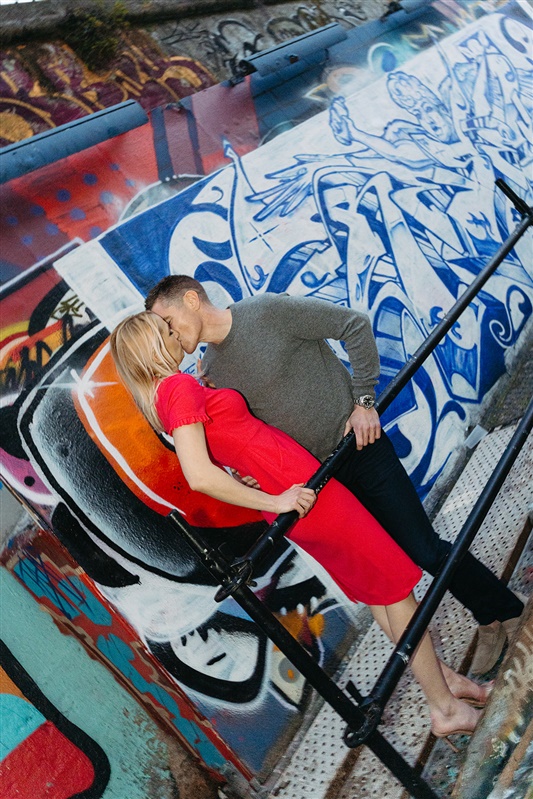 Artistic couple portrait kissing beside colorful street art during a Lisbon engagement style photo session