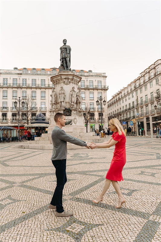 Couple holding hands during a romantic photo session at Praça do Comércio in Lisbon, Portugal