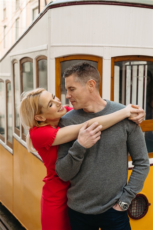 Romantic portrait of a couple embracing beside a traditional yellow tram in Lisbon